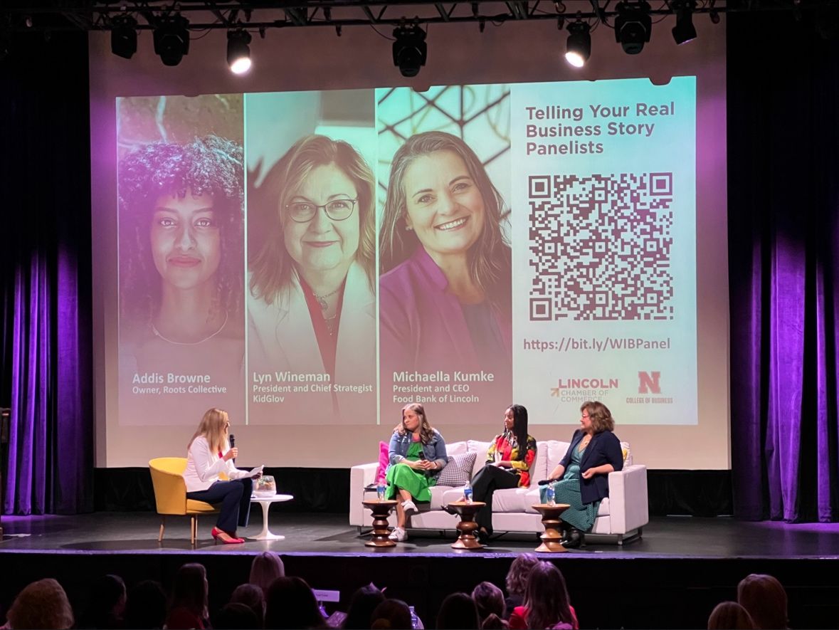 Four business leaders in a moderated conference panel on a professionally lit stage