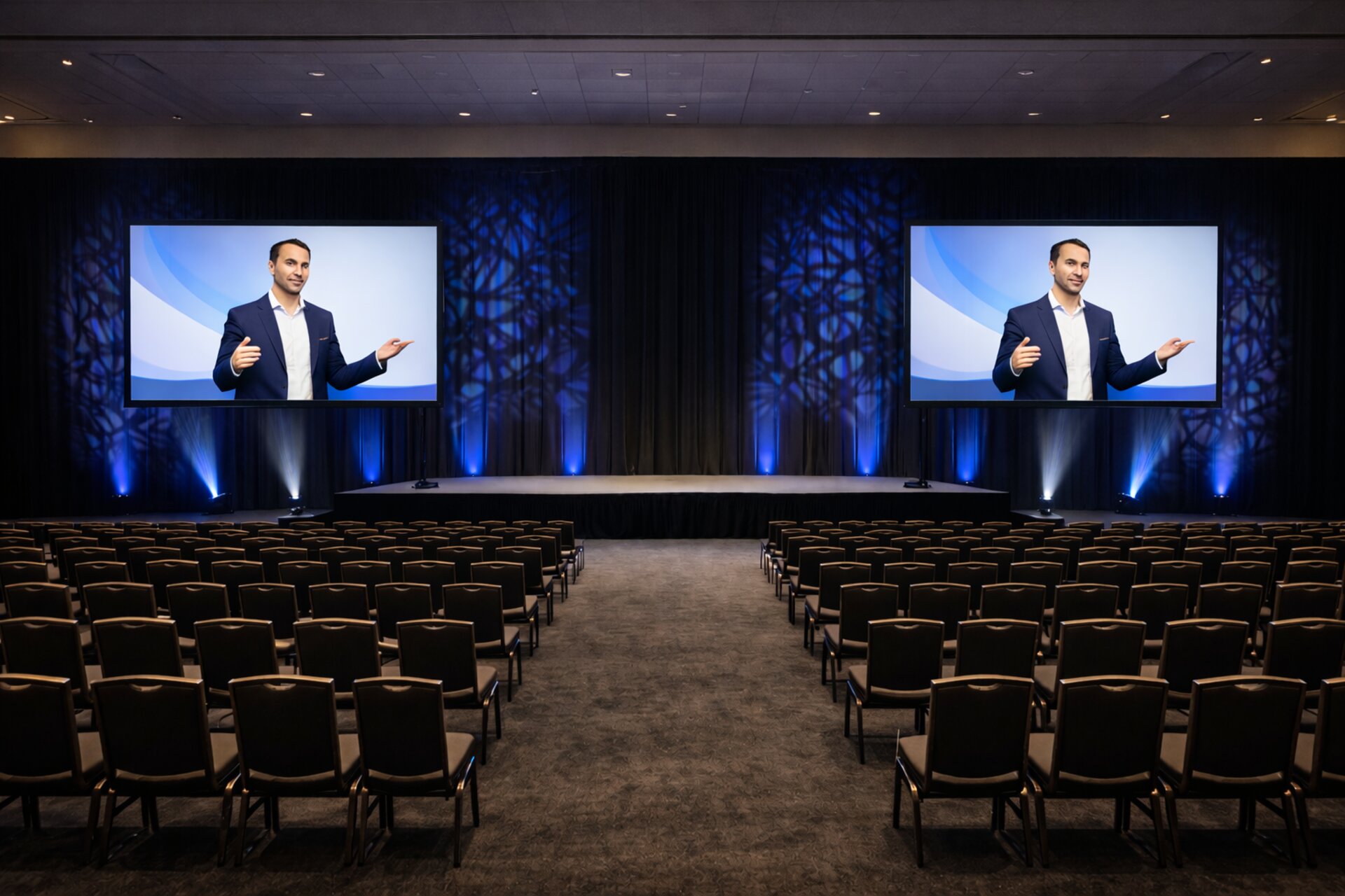Pre-production render of a general session stage with dual screens and blue lighting